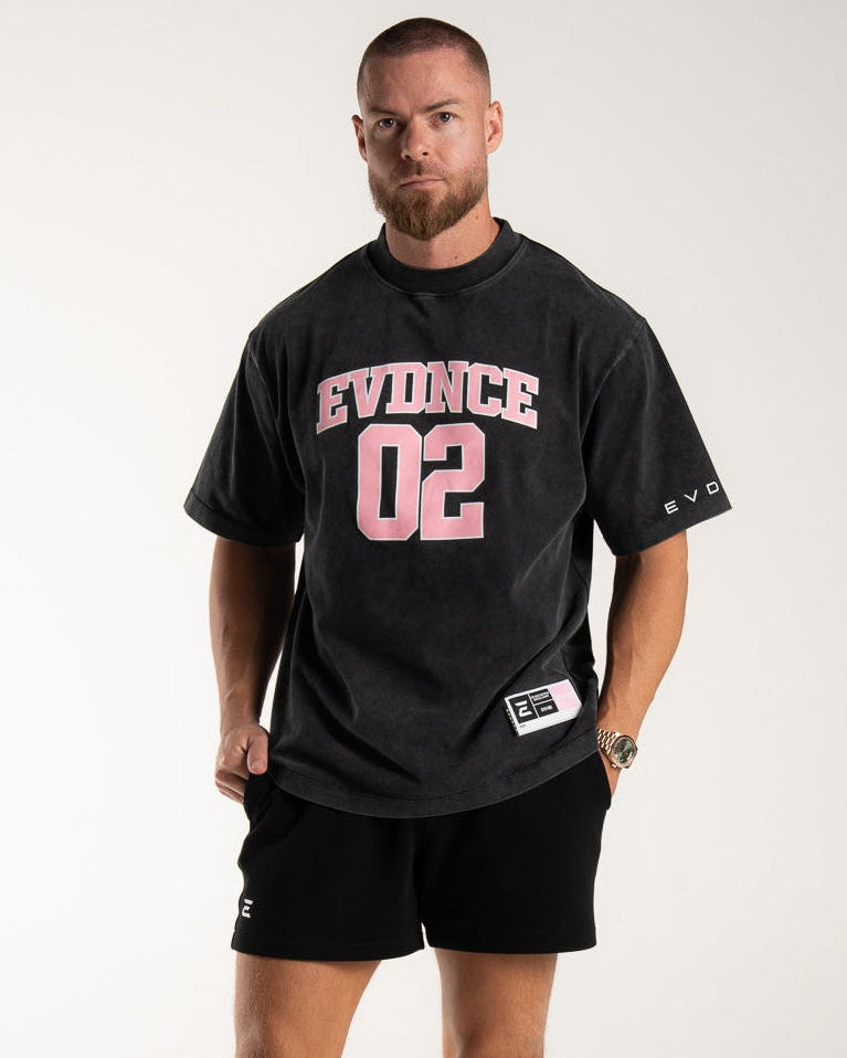 Model wearing the EVDNCE 02 Oversized Tee in Washed Black, front view, styled with matching shorts in studio lighting.