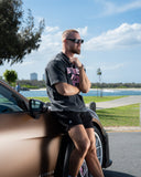 [men] Man leaning against a Porsche GT3 RS by a waterfront with a scenic background wearing a washed black EVDNCE 02 Oversized Tee